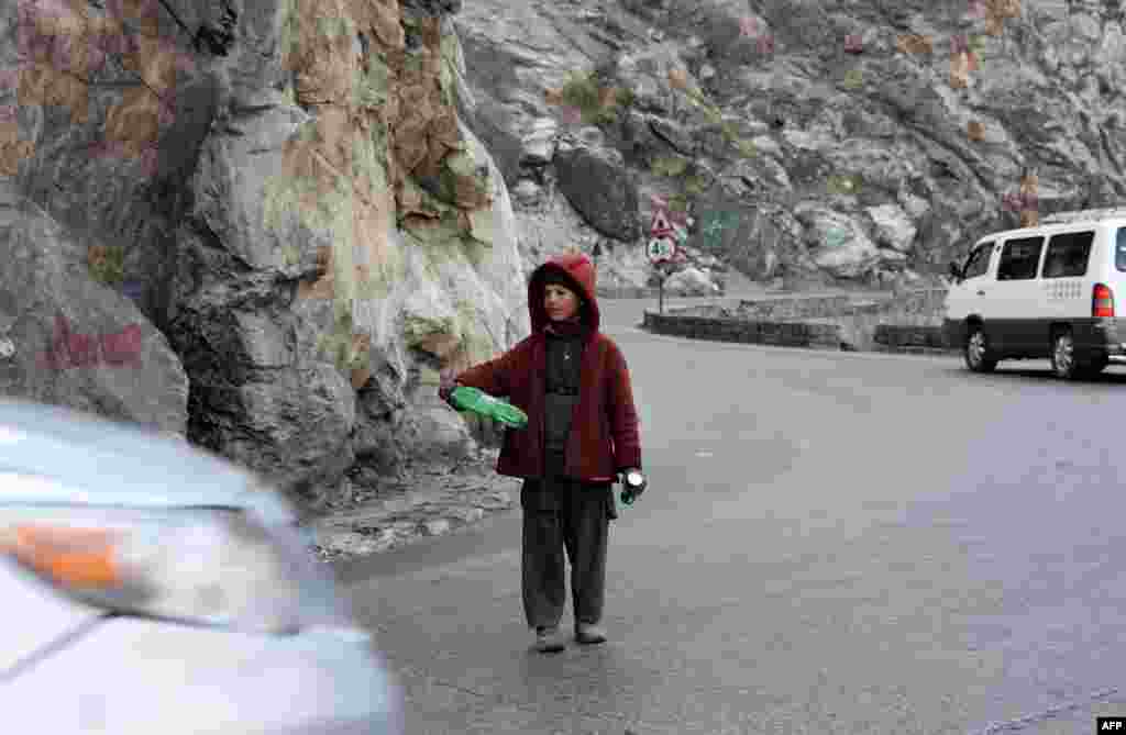 Eight-year-old Hedayat guides traffic through the Mahipar Gorge along the Kabul-Jalalabad Highway in Afghanistan. Hedayat, the eldest son of his six-member family, guides traffic with his bottle from dawn to dusk on the highway, making roughly $3 a day. Poverty and insecurity have forced thousands of children into child labor in Afghanistan. Instead of attending school, many children aged 5 to 15 work on the streets and are often the sole breadwinners for their families. (AFP/Noorullah Shirzada)