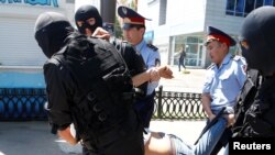Полицейские и сотрудники служб быстрого реагирования задерживают активиста при попытке митинга протеста 21 мая 2016 года в Алматы.