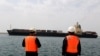Workers watch a ship as it sails during an inauguration ceremony of new equipment and infrastructure at Shahid Beheshti Port in the Southeastern Iranian coastal city of Chabahar, on the Gulf of Oman. FILE PHOTO
