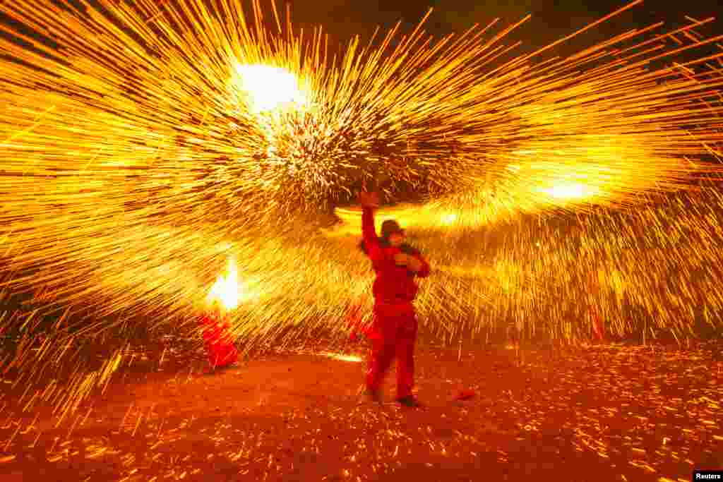 A folk artist makes a shower of sparks with molten iron during a local celebration ahead of the Chinese Lantern Festival, in Luzhou, Sichuan Province, China. (Reuters/Stringer)