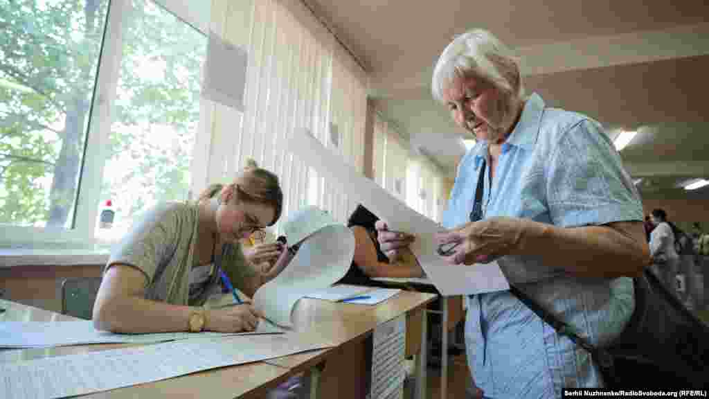 An elderly woman examines her ballot in Kyiv. (RFE/RL/Serhii Nuzhnenko)