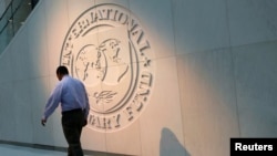 U.S. -- A man walks past the International Monetary Fund logo at its headquarters in Washington, May 10, 2018.