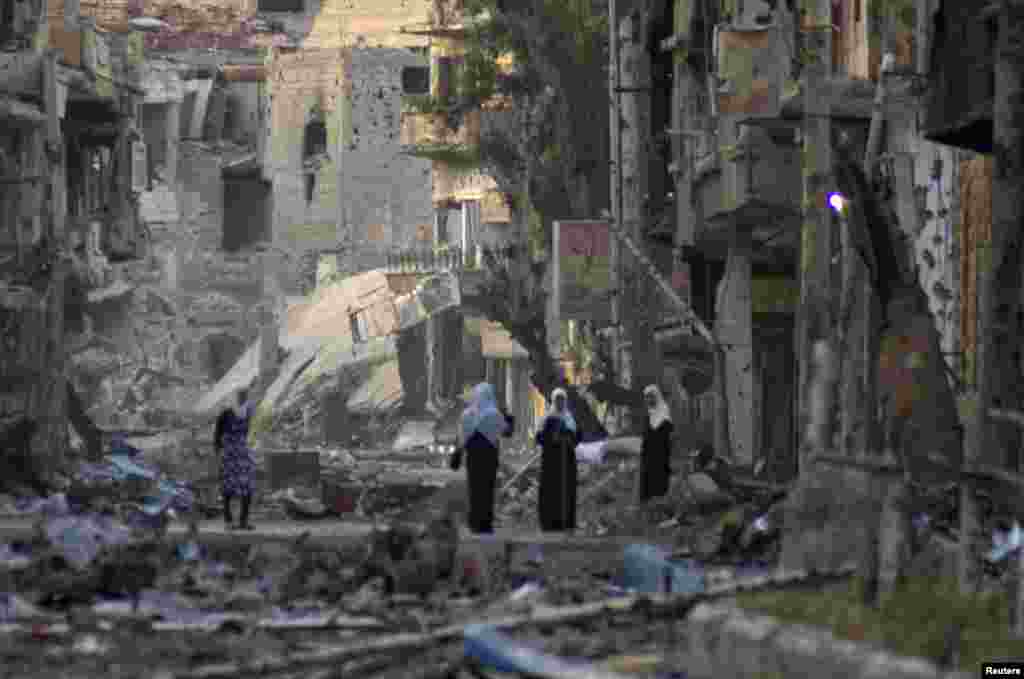 Syria -- Women stand in a street lined with damaged buildings in Deir al-Zor, 07Apr2013