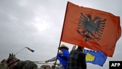 Kosovo Albanians ride a horse-drawn cart decorated with Kosovo and Albanian flags near the town of Mitrovica in February.