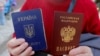 UKRAINE – A woman poses with a Ukrainian and a Russian passport outside an office of the Russian Federal Migration Service, where she received a Russian passport, in the Crimean city of Simferopol, April 7, 2014