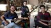 In this Thursday, July 26, 2018, photo, Afghan musicians Mohammad Rezai, right, Hakim Ebrahimi, left, and Soraya Hosseini, members of the Arikayn rock band, pose for a photo at a furniture workshop in Pakdasht, outside Tehran, Iran. The band, made up of A