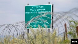 Georgia -- A warning sign is pictured behind a wire barricade erected by Russian and South Ossetian troops along Georgia's de-facto border with its breakaway region of South Ossetia in the village of Khurvaleti, July 14, 2015