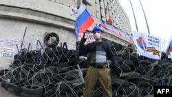 Человек в маске на баррикадах перед зданием администрации в Донецке. 10 апреля 2014 года.