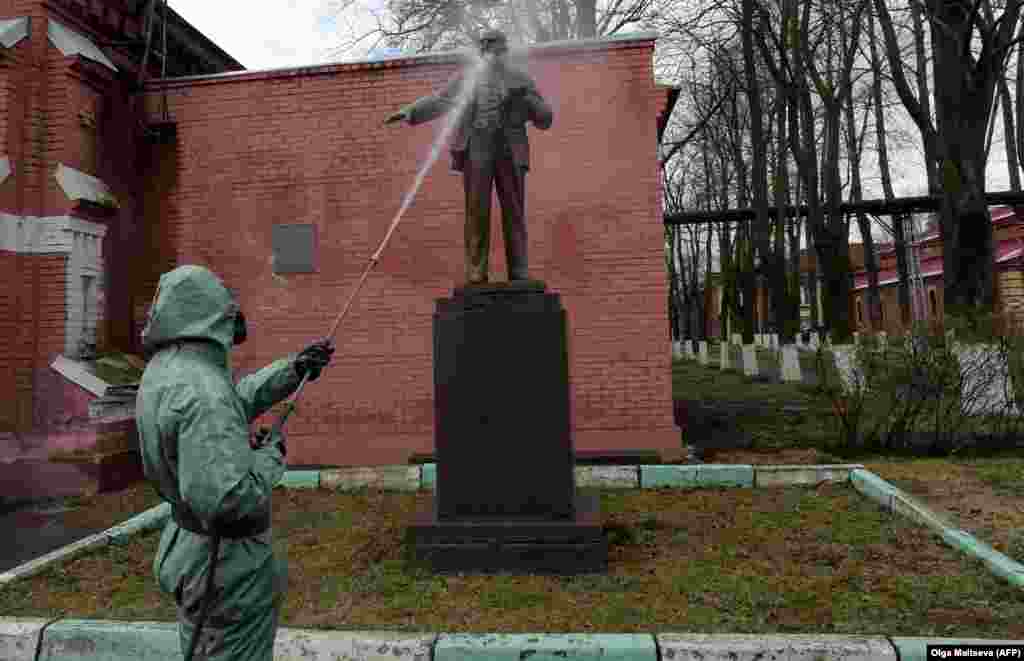 A Russian serviceman wearing a protective suit sprays disinfectant on a monument to the Soviet leader Vladimir Lenin while sanitizing an industrial area in St. Petersburg. (AFP/Olga Maltseva)