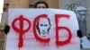A demonstrator in Moscow holds up a sign saying "FSB" with a portrait of Vladimir Putin demanding freedom for political prisoners. The FSB is "closed in on itself and accounts to no one. In that sense, the FSB now is more frightening and more powerful than the KGB was," an NGO lawyer says.