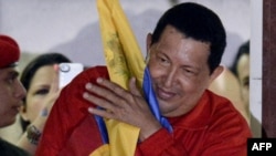 President Hugo Chavez, sporting his red tracksuit, embraces a Venezuelan flag while speaking to supporters after receiving news of his reelection on October 7. 