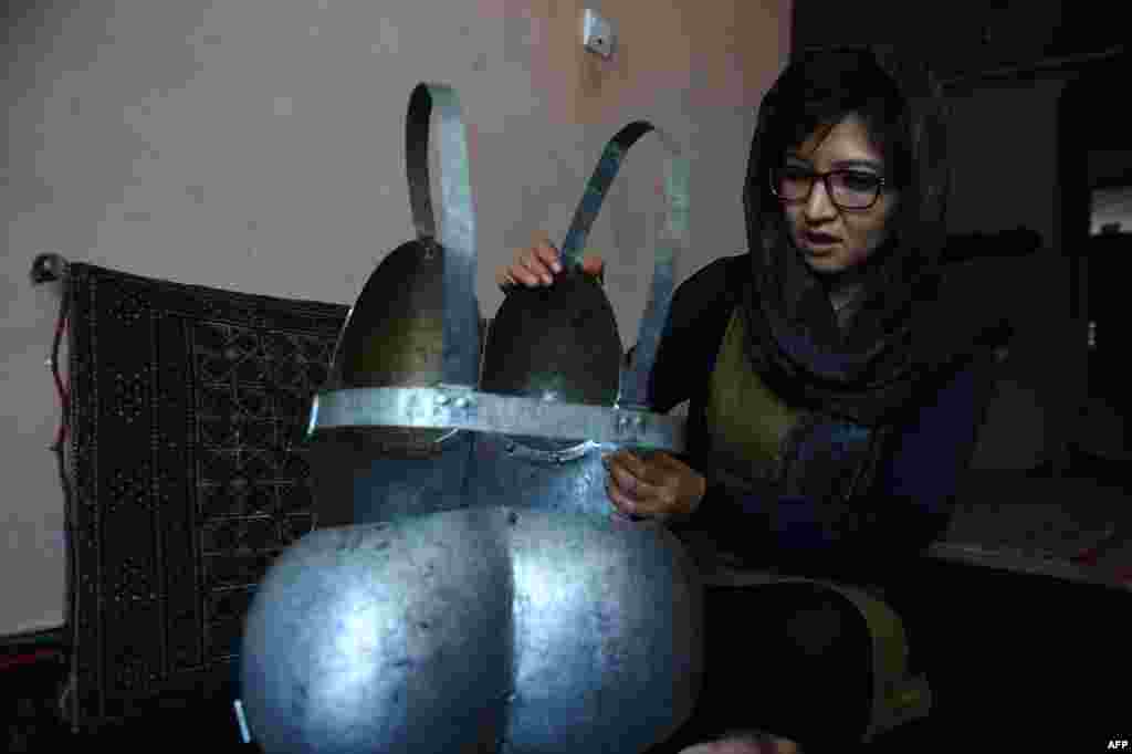 Afghan artist Kubra Khademi, 27, sits alongside a suit of armor she made as a protest against sexual harrassment. (AFP/Shah Marai)