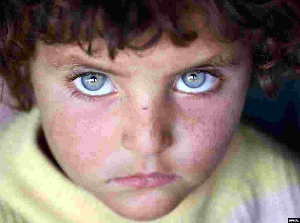 An Afghan girl sits outside a temporary shelter at a refugee camp in Kabul on July 8. Nearly 300,000 Afghans remain displaced within their own country, and nearly 3 million more are refugees abroad, mainly in Pakistan and Iran. Photo by RFE/RL