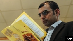 Pakistani investigative journalist Umar Cheema glances at his report prior to addressing a news conference in Islamabad on December 12.