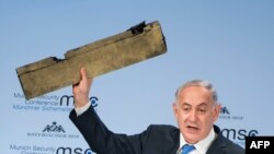 Premierul Benjamin Netanyahu ține un obiect despre care spune că e o piesă din drona iraniană doborît în spațiul aerian în timp ce vorbește la Conferința internațională de securitate de la Muenchen, 18 februarie 2018.