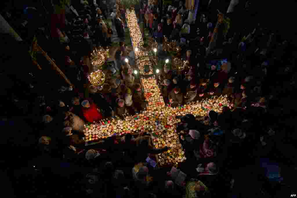Orthodox Christians pray around a cross-shaped platform covered with candles placed in jars of honey during a ceremony marking the feast day of Saint Haralampi, the Orthodox patron saint of beekeepers, at a church in eastern Bulgaria on February 10. (AFP/Nikolay Doychinov)