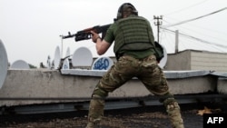 A pro-Russia militant shoots from a roof of a residential building at border guards defending the Federal Border Headquarters building in Luhansk on June 2.