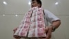 Сотрудник китайской фирмы несет пачки банкнот достоинством в 100 юаней. Тайюань, 4 июля 2013 года.