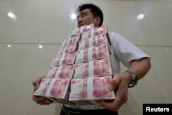 Қытай юанін көтеріп келе жатқан банк қызметкері. Қытай, 4 шілде 2013 жыл. (Көрнекі сурет)