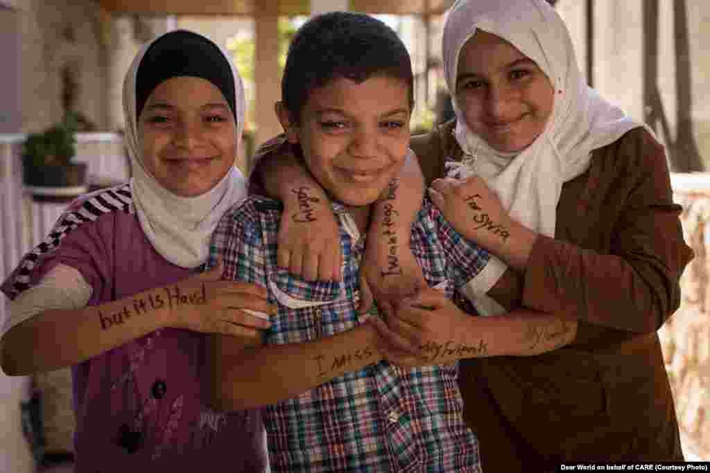Мальчик: «Я скучаю по моим друзьям, по моей семье». Девочка слева: «Я хочу вернуться в Сирию, но это трудно». Девочка справа: «Безопасность для Сирии». Организация CARE предоставляет семьям этих беженцев и другим людям экстренную денежную помощь, чтобы помочь им удовлетворить их неотложные потребности.