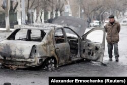 Un om lângă o mașină distrusă în bombardamente în Donețk, 22 ianuarie, 2015.