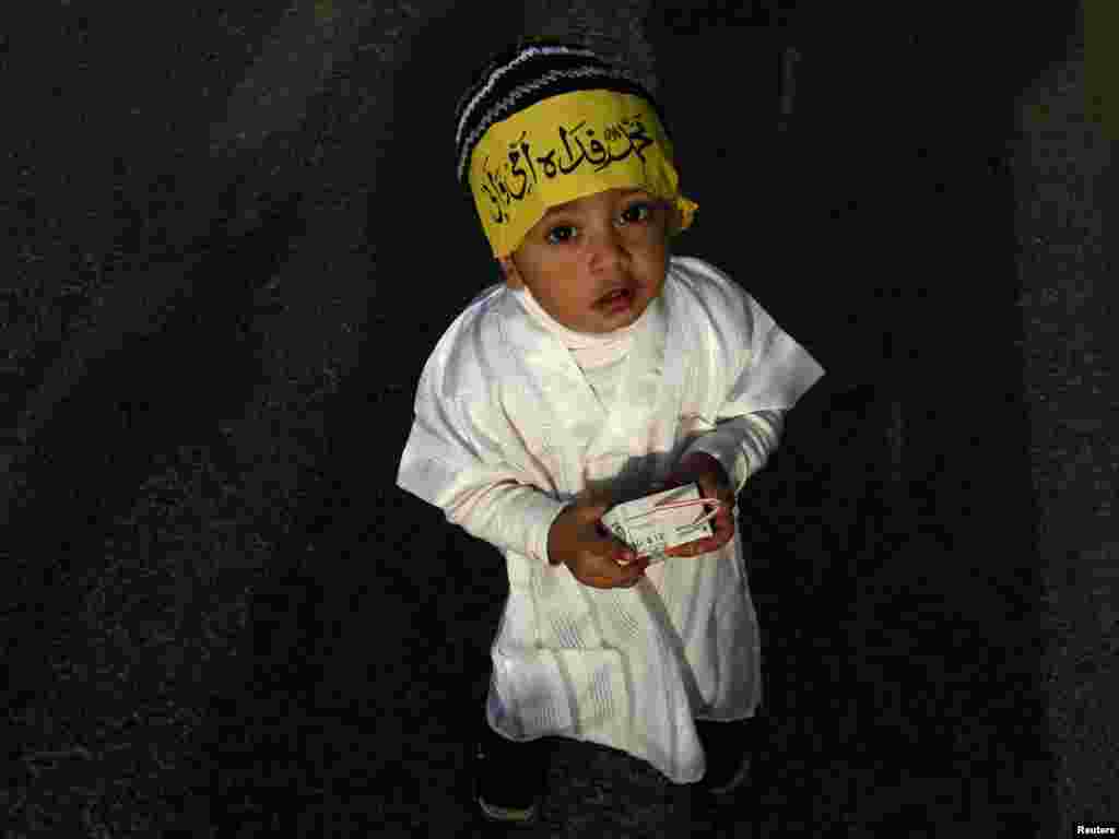 A 3-year-old Pakistani boy wears a headband that reads, "Muhammad, may my mother and father lay their lives for you." Photo by Athar Hussain for Reuters