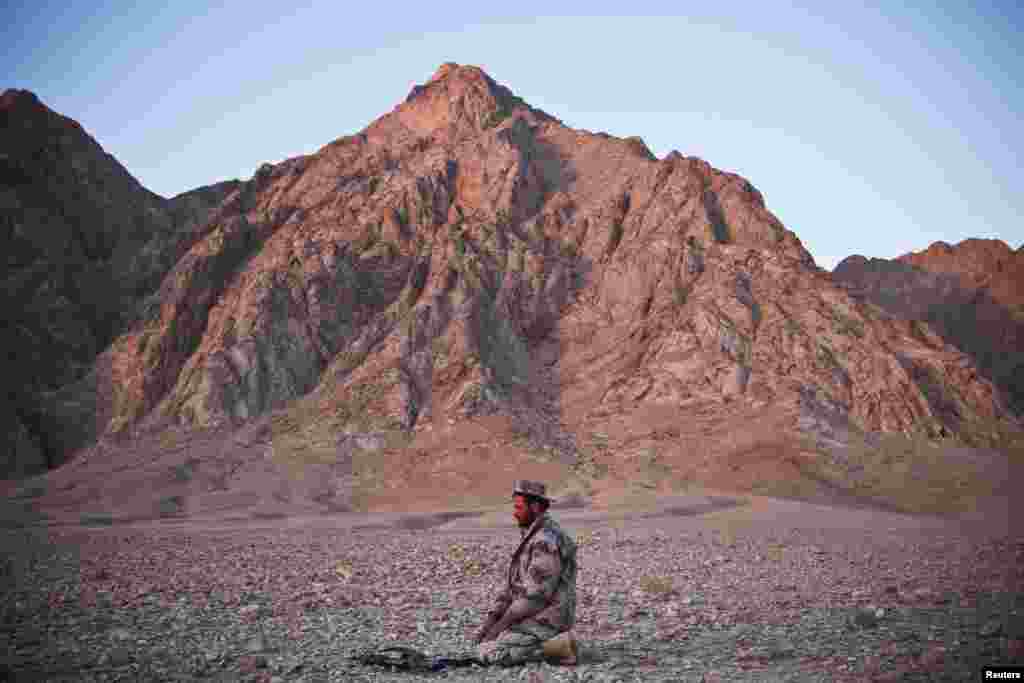 A member of the Afghan National Police prays at sunset before the detonation of confiscated improvised explosive devices (IEDs) near Combat Outpost Hutal in Kandahar Province. (Reuters/Andrew Burton)