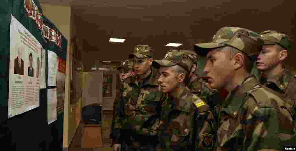 Soldiers read information about the candidates at a polling station in Minsk.