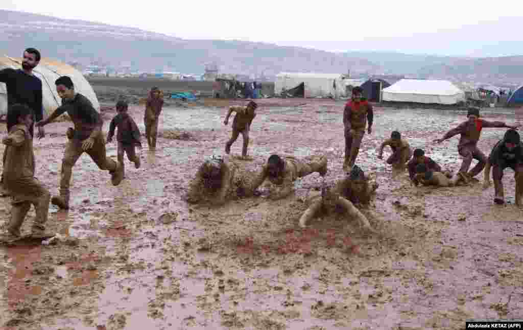 Syrians play a game of football organized by local activists in a muddy field in a camp for the internally displaced in Syria's northwestern province of Idlib. (AFP/Abdulaziz Ketaz)