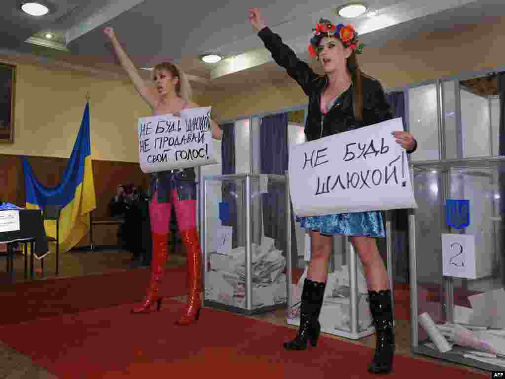 In Kyiv, activists of the "Femen" women's organization hold posters reading "Don't be a whore! Don't sell your vote!"