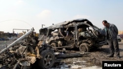 A resident stands near burned vehicles after a car-bomb attack in Baghdad's Kadhimiyah district on February 8.