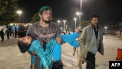 An Afghan man carries a wounded girl after an attack by gunmen at the Karte Sakhi shrine in Kabul on October 11.