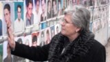 Kosovo - Nesrete Kumnova, head of the Mothers Appeal Association, in front of a wall with photos of missing people in Pristina, Nov2007