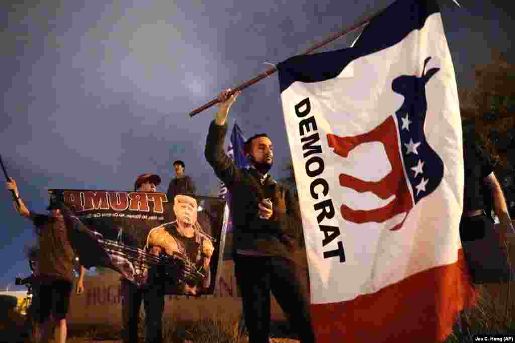 A supporter of Democrat Joe Biden waves a flag in front of the Clark County Election Department, Thursday, Nov. 5, 2020, in Las Vegas. (AP Photo/Jae C. Hong)
