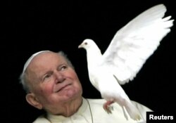 Папа Іван Павло Другий дивиться на голуба, якого випустили діти задля миру у Ватикані
