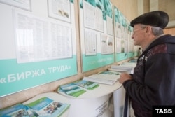 Egy férfi egy omszki orosz munkaügyi központban ellenőrzi az állásajánlatok listáját (archív fotó)