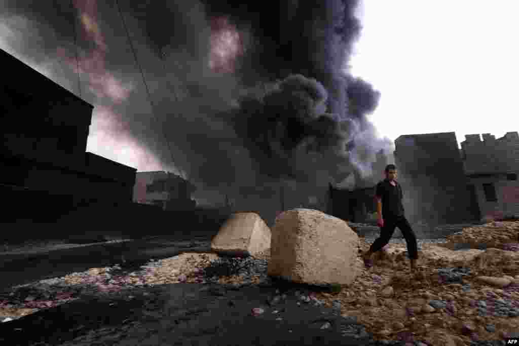 An Iraqi man walks near smoke billowing from oil wells set ablaze by Islamic State militants before they fled the oil-producing region of Qayyarah on August 30. (Safin Hamed/AFP)