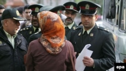 Iranian policemen warn a woman about her clothing and hair during a crackdown to enforce the Islamic dress code in Tehran.