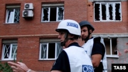 OSCE observers inspect a site near residential buildings damaged by recent shelling in Donetsk on September 9.