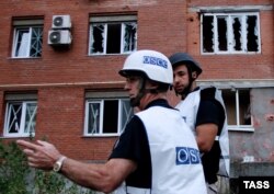 Observatori OSCE examinează o clădire bombardată în Donețk.