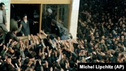 Some of the thousands of people who on daily basis jammed a schoolyard in Tehran to see the Ayatollah Rouhollah Khomeini immediately after his return to Iran, who blesses the crowd, is pictured, Feb. 4, 1979. 