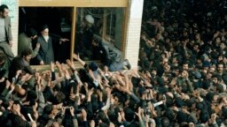 Some of the thousands of people who on daily basis jammed a schoolyard in Tehran to see the Ayatollah Rouhollah Khomeini immediately after his return to Iran, who blesses the crowd, is pictured, Feb. 4, 1979. 