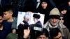 A man holding a picture of Qassem Soleimani and Supreme Leader Ali Khamenei during the march against the Qods Force commander's killing. 