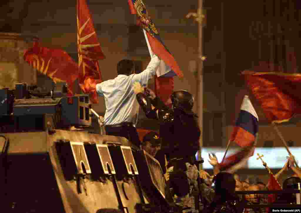 A police officer tries to grab a protester from atop of a police vehicle during a protest against a deal between Greece and Macedonia on the latter country's new name of North Macedonia, outside the parliament in Skopje. (AP/Boris Grdanoski)