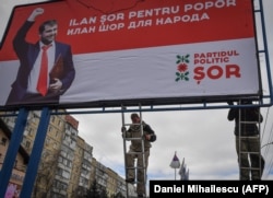 Workers hang an election campaign billboard in Chisinau in February 2019 depicting Moldova's parliamentary candidate Ilan Shor and reading both in Romanian and Russian: "Ilan Shor [is] for the people." (file photo)