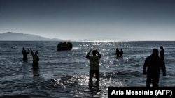 Members of the nonprofit organisation Emergency Response Centre International (ERCI) gesture from the shore to a boat carrying refugees and migrants as it arrives in Mytilene on the northern Greek island of Lesbos, after crossing the Aegean Sea.