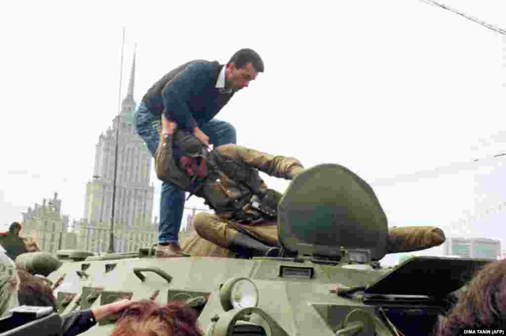 Un demonstrant pro-democrație se luptă cu un soldat sovietic deasupra unui tanc parcat în fața clădirii Federației Ruse, la 19 august 1991, după ce o lovitură de stat l-a răsturnat pe președintele sovietic Mihail Gorbaciov. Lovitura de stat a fost condusă de către membrii autointitulatului &bdquo;comitet pentru starea de urgență&rdquo; sau &bdquo;banda celor opt&rdquo;. Aceștia&nbsp;l-au închis pe Mihail Gorbaciov în cabana sa din Crimeea și au încercat să mențină o URSS unită prin forță. Mii de oameni din Moscova, Leningrad și alte orașe au răspuns în aceeași zi apelului președintelui Republicii Ruse, Boris Elțîn, de a ridica baricade împotriva tancurilor și a trupelor. După eșecul loviturii de stat, Partidul Comunist a fost interzis, iar Uniunea Sovietică s-a destrămat oficial în cursul aceluiași an, punând pe hartă 15 țări independente.