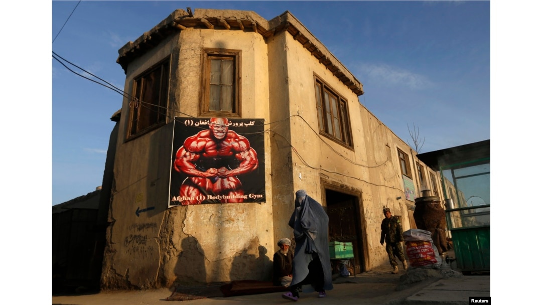 An Afghan woman in a burqa walks past a gym billboard in Kabul. (file photo)