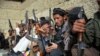 FILE: Afghan anti IS volunteers sit with their weapons in eastern Afghanistan.