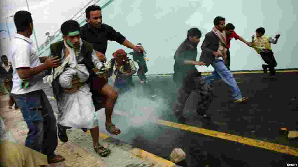 Protesters run as riot police fire tear gas at them outside the U.S. Embassy in Sanaa, Yemen. (Reuters/Khaled Abdullah)